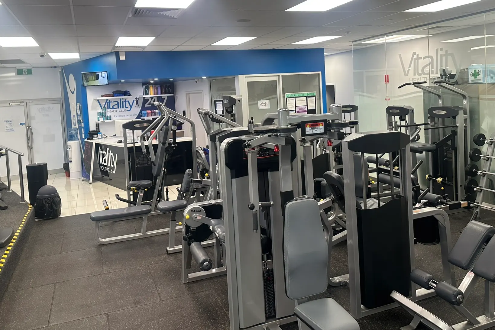 The reception desk at the Berri club, with the Vitality name on the blue wall behind it and the strength machines on the floor in front
