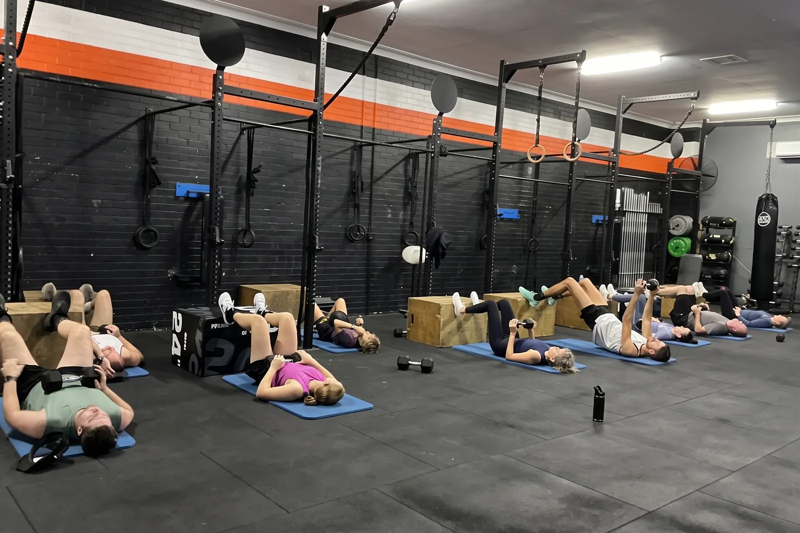 A class at Renmark working through a floor set on mats, dumbbells overhead, under the rig